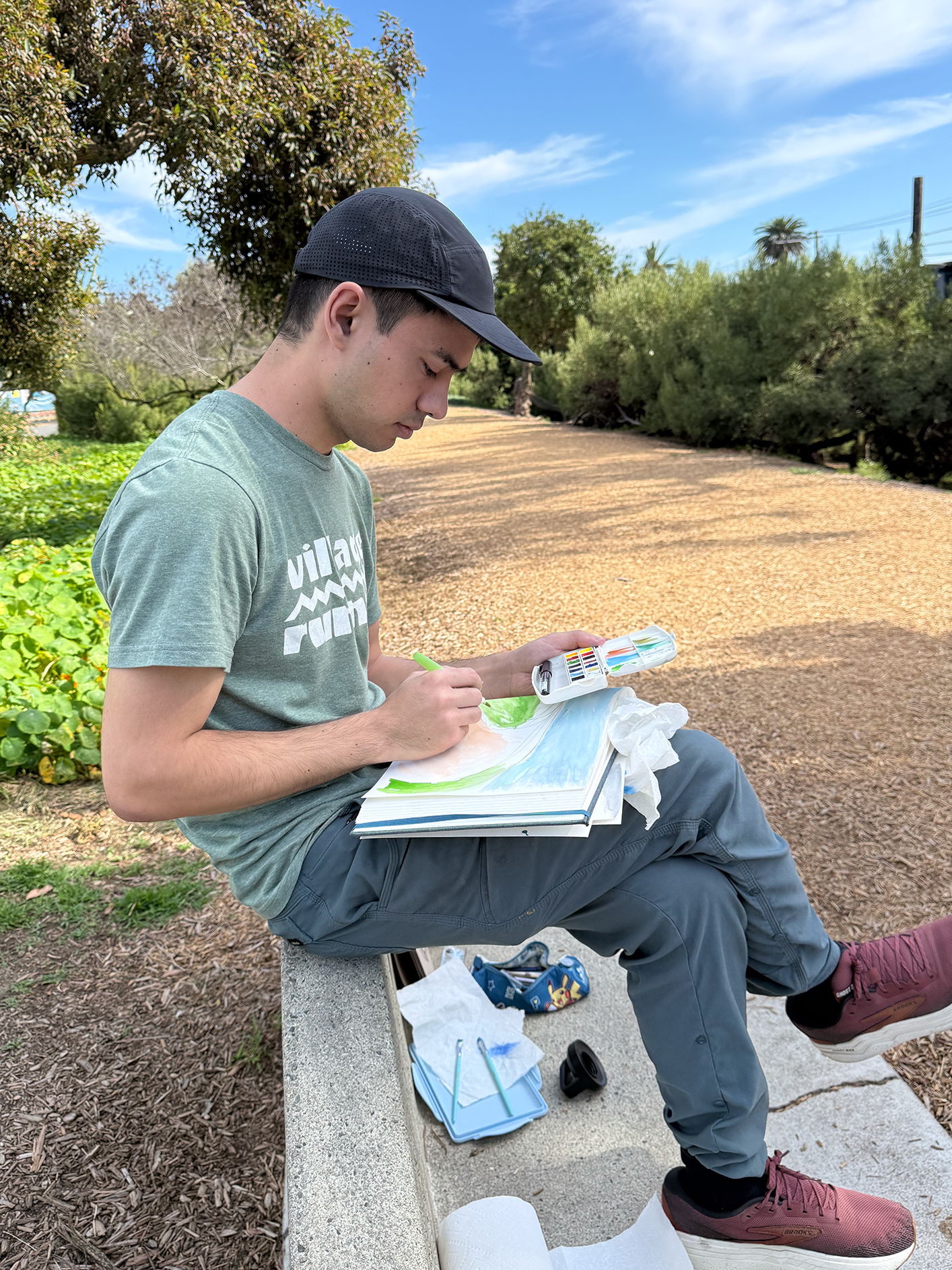 Person sitting outdoors, using watercolor in a plein air workshop